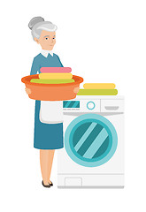 Image showing Senior housewife using washing machine at laundry.