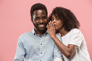 Image showing The young woman whispering a secret behind her hand to afro man