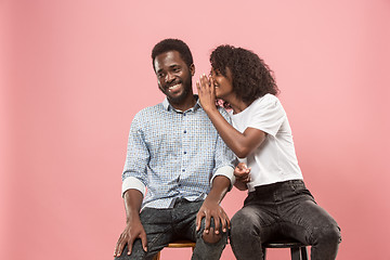 Image showing The young woman whispering a secret behind her hand to afro man