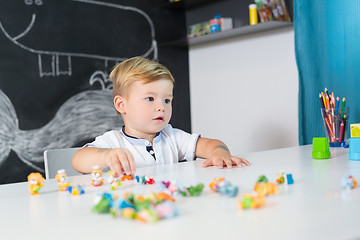 Image showing Portrait of cute toddler boy playing with toys at the desk at home.