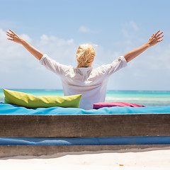 Image showing Relaxed woman in luxury lounger, arms rised, enjoying summer vacations on beautiful beach.