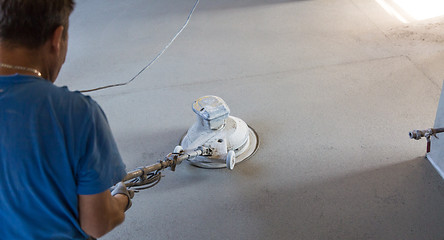 Image showing Laborer polishing sand and cement screed floor.