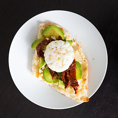 Image showing Poached egg on a toasted bun with avocados and dried tomatoes