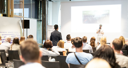 Image showing Businessman in audience standing and asking question to speeker at business conference.