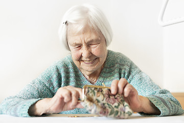 Image showing Cheerful elderly 96 years old woman sitting at table at home happy with her pension savings in her wallet after paying bills.