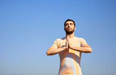 Image showing man meditating outdoors over sky