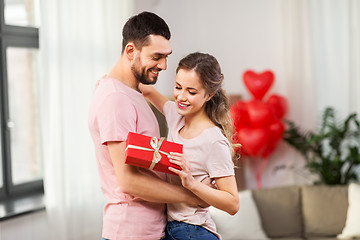 Image showing happy couple with gift box hugging at home