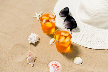 Image showing cocktails, sun hat and sunglasses on beach sand