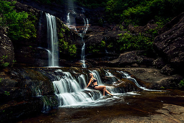 Image showing Woman basking in lush mountain waterfall