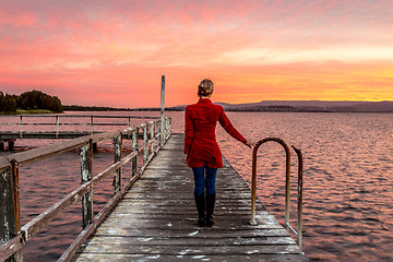 Image showing Woman on rustic timber jetty watching beautiful sunset