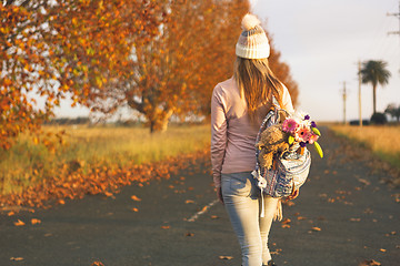 Image showing Woman walking along a country road in Autumn