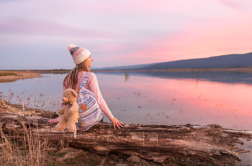 Image showing Relaxed woman watching a serene sunset by the lake