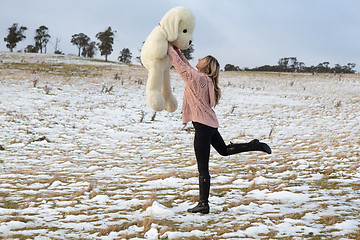 Image showing Woman frolicking in the snow with teddy bear