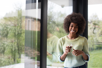 Image showing African American woman drinking coffee looking out the window