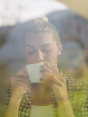 Image showing young woman drinking morning coffee by the window