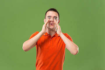 Image showing Isolated on green young casual man shouting at studio