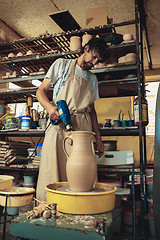 Image showing Creating a jar or vase of white clay close-up. Master crock.