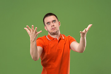 Image showing Beautiful male half-length portrait isolated on green studio backgroud. The young emotional surprised man