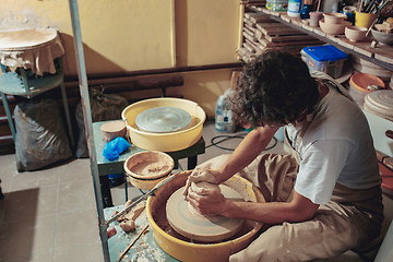 Image showing Creating a jar or vase of white clay close-up. Master crock. Man hands making clay jug macro.