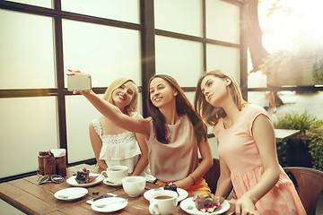 Image showing Two girl friends spend time together drinking coffee in the cafe, having breakfast and dessert.