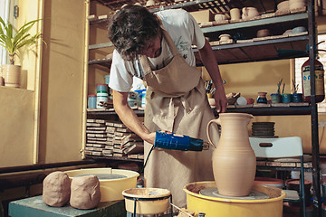 Image showing Creating a jar or vase of white clay close-up. Master crock.