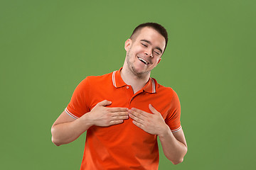 Image showing Beautiful male half-length portrait isolated on green studio backgroud. The young emotional surprised man