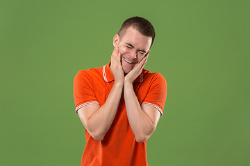 Image showing Beautiful male half-length portrait isolated on green studio backgroud. The young emotional surprised man