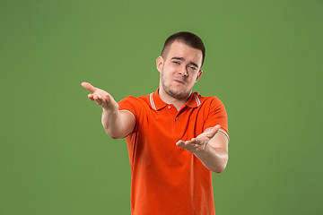 Image showing Beautiful male half-length portrait isolated on green studio backgroud. The young emotional surprised man