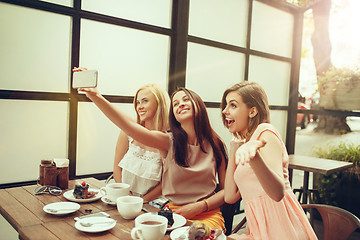 Image showing Two girl friends spend time together drinking coffee in the cafe, having breakfast and dessert.