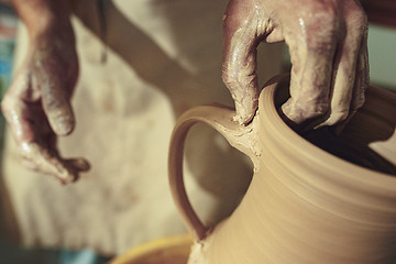 Image showing Creating a jar or vase of white clay close-up. Master crock. Man hands making clay jug macro.