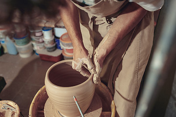 Image showing Creating a jar or vase of white clay close-up. Master crock. Man hands making clay jug macro.