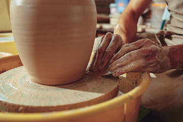 Image showing Creating a jar or vase of white clay close-up. Master crock. Man hands making clay jug macro.