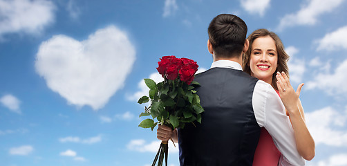 Image showing woman with engagement ring and roses hugging man