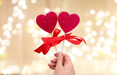 Image showing close up of hand holding red heart shaped lollipop