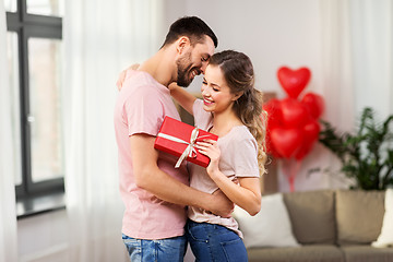 Image showing happy couple with gift box hugging at home