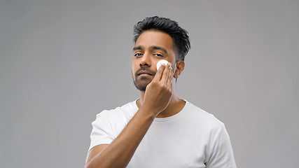 Image showing smiling indian man cleaning face with cotton pad