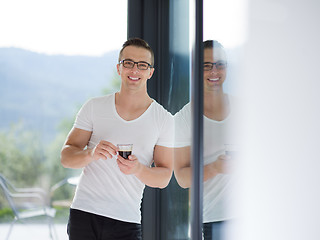 Image showing young man drinking morning coffee by the window