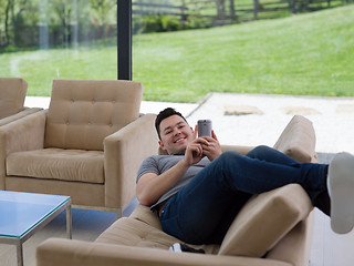 Image showing young man using a mobile phone  at home