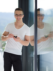 Image showing young man drinking morning coffee by the window