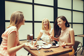 Image showing Two girl friends spend time together drinking coffee in the cafe, having breakfast and dessert.