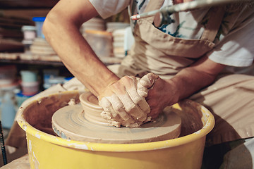 Image showing Creating a jar or vase of white clay close-up. Master crock. Man hands making clay jug macro.