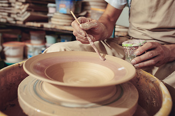 Image showing Creating a jar or vase of white clay close-up. Master crock. Man hands making clay jug macro.