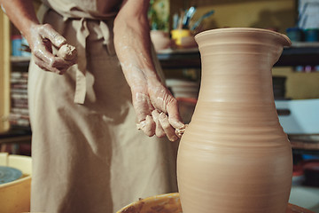 Image showing Creating a jar or vase of white clay close-up. Master crock. Man hands making clay jug macro.