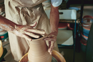 Image showing Creating a jar or vase of white clay close-up. Master crock. Man hands making clay jug macro.