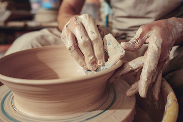 Image showing Creating a jar or vase of white clay close-up. Master crock. Man hands making clay jug macro.