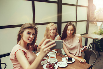 Image showing Two girl friends spend time together drinking coffee in the cafe, having breakfast and dessert.