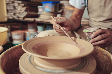 Image showing Creating a jar or vase of white clay close-up. Master crock. Man hands making clay jug macro.