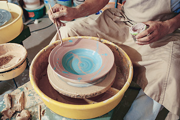 Image showing Creating a jar or vase of white clay close-up. Master crock. Man hands making clay jug macro.