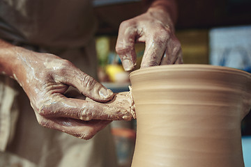 Image showing Creating a jar or vase of white clay close-up. Master crock. Man hands making clay jug macro.