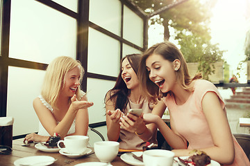 Image showing Two girl friends spend time together drinking coffee in the cafe, having breakfast and dessert.